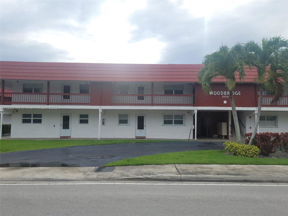 Front view of a two-story building with a red roof and a driveway at the entrance.