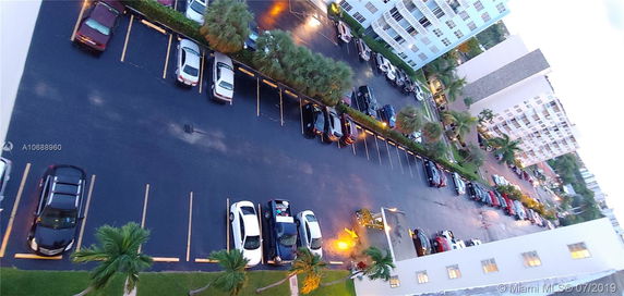 View from above of a parking lot adjacent to a multi-story residential building.
