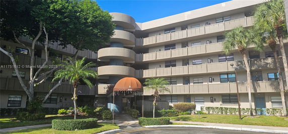Front view of a multi-story residential building with balconies and a brown awning entrance.