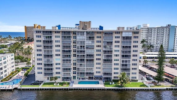 Front view of a multi-story residential building with a swimming pool and waterfront location.
