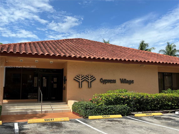 Front view of a building with a tiled roof and 'Cypress Village' signage.