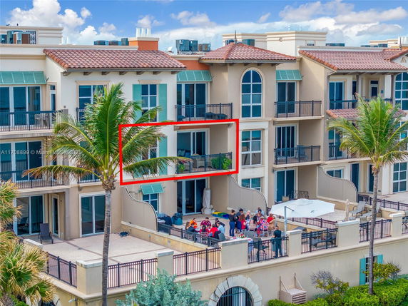View of a multi-story residential building with balconies and people gathered on a terrace.
