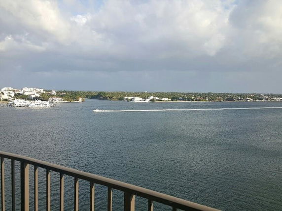 View from a building overlooking a large body of water with a distant shoreline and cloudy sky.