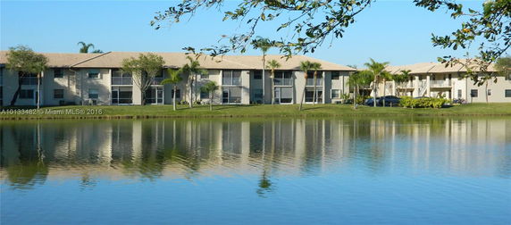 View of multiple residential buildings with reflective water in the foreground.