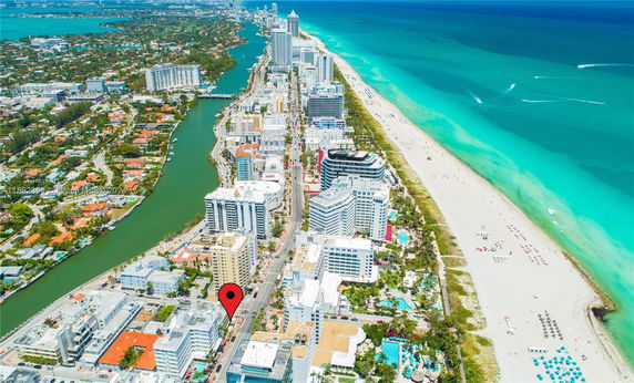 Aerial view of a coastal city with beach, ocean, and numerous buildings.