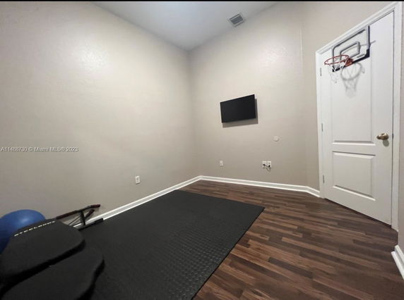 Room with a small basketball hoop attached to the door and exercise equipment