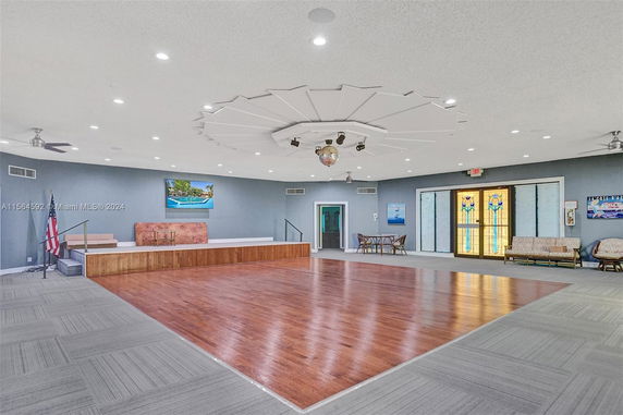 Interior of a spacious recreation room with wood flooring and a small stage.