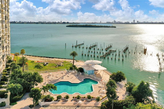 Panoramic view overlooking a waterfront with a swimming pool and surrounding area.