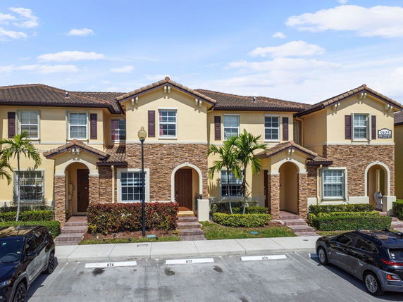 Front view of a two-story townhouse with a brick facade and arched entrance.