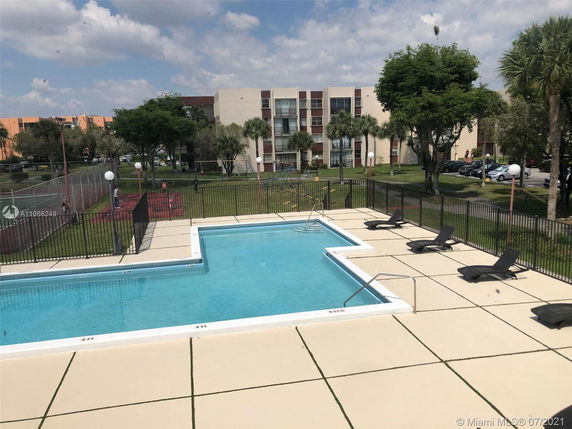 Outdoor swimming pool with lounge chairs and fenced area.