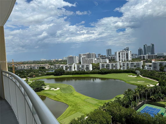 Panoramic view of a cityscape with buildings, a golf course, and a tennis court.