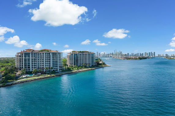 Aerial view of waterfront buildings with a city skyline in the background.