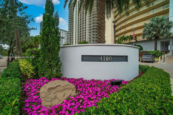 Front view of a multi-story residential building with a curved facade and well-maintained landscaping.