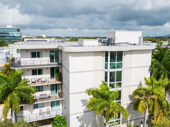 Front view of a multi-story apartment building with balconies and large windows.
