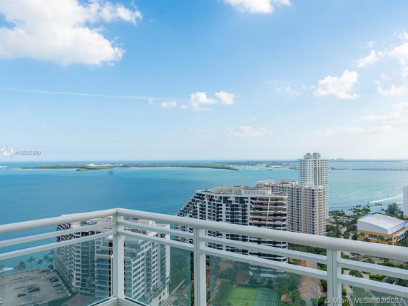 Panoramic view of high-rise buildings and a large body of water from a balcony.