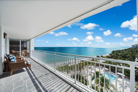 Wide-angle view from a balcony overlooking the ocean and a beachfront area.