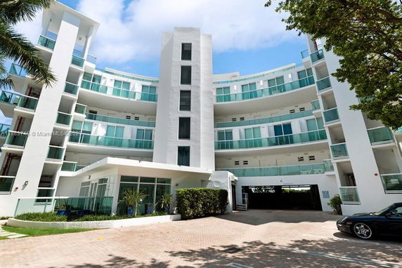 Front view of a modern multi-story building with curved balconies and glass railings.