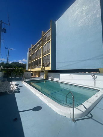 Outdoor swimming pool beside a multi-story building.