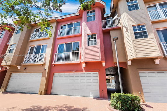 Front view of a multi-story townhouse with multiple balconies and a garage.