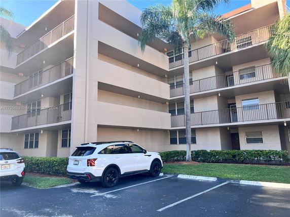 Front view of a multi-story apartment building with parking spaces.