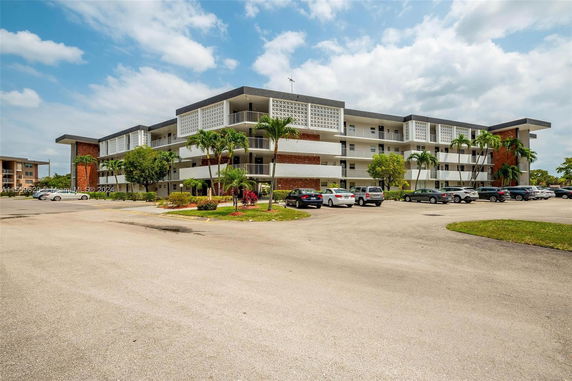 Front view of a multi-story residential building with parking area.