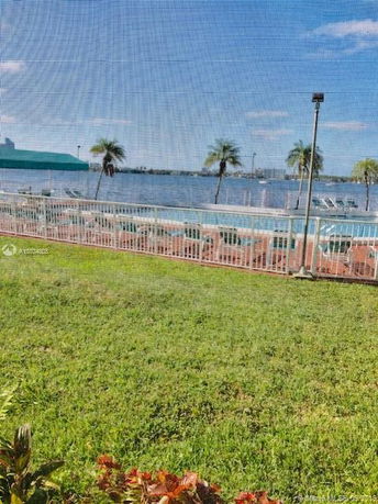 View of a waterfront area with palm trees and a fenced outdoor pool.