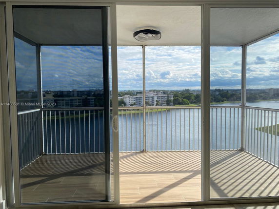 Panoramic view of water and nearby buildings from a balcony with glass doors.