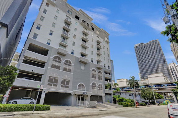 Front view of a multi-story building with balconies and parking area.