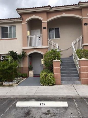 Front view of a two-story residential building with outdoor stairs and a numbered parking spot.