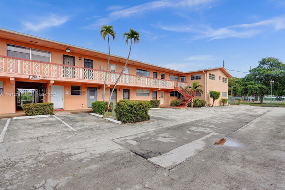 Front view of a two-story residential building with an open parking area.