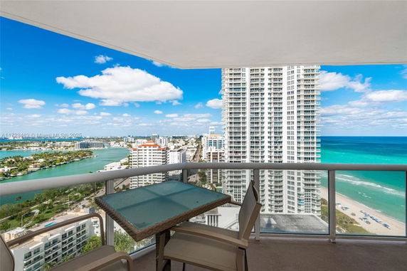 Panoramic view from a balcony overlooking the ocean and high-rise buildings.