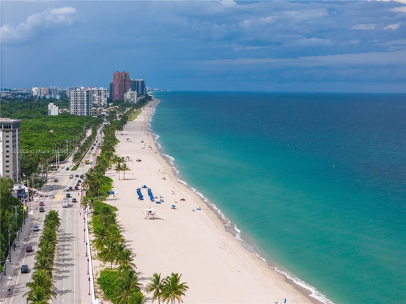 Wide angle view of a beachline with buildings and road beside the ocean.