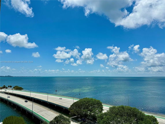 Panoramic view of a bridge and ocean under a partly cloudy sky.