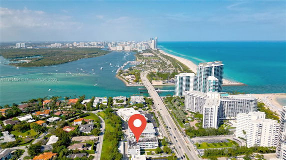 Aerial view of a coastal area with buildings, roads, and a wide expanse of blue ocean.
