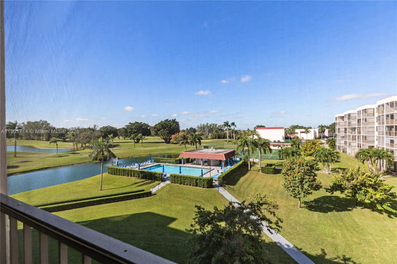 View of surrounding areas including a pool and green landscape.