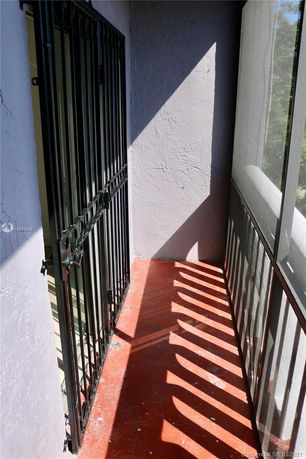 Narrow balcony with metal railings and a concrete floor.