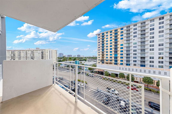 View from a balcony overlooking a street with high-rise apartment buildings.