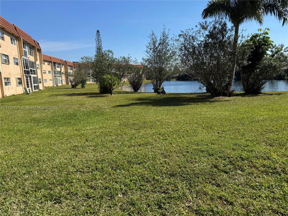 View of a multi-story building near a lake with surrounding greenery.