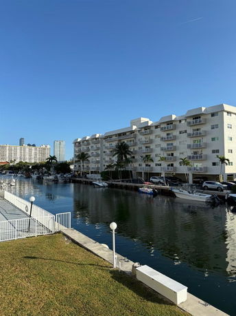 Front view of a multi-story building beside a canal with parked boats.