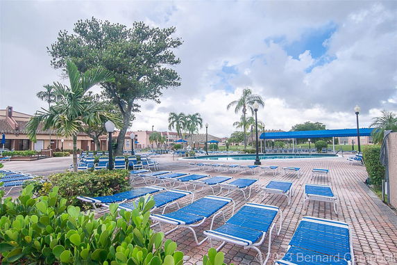Outdoor swimming pool area with lounge chairs and surrounding buildings.