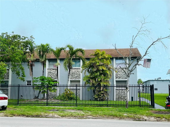 Front view of a two-story building with distinct stone detailing and a fenced yard.