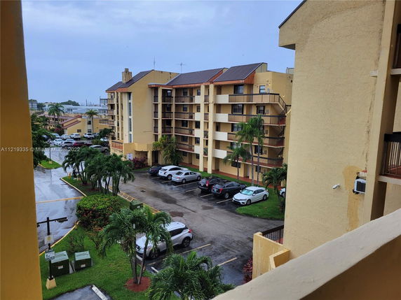 View of a parking area next to multiple yellow residential buildings.