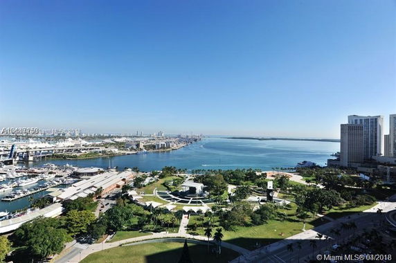 Panoramic view of a coastal cityscape with buildings, greenery, and waterfront.