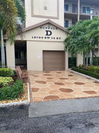 Front view of a multi-story building entrance with a patterned walkway.