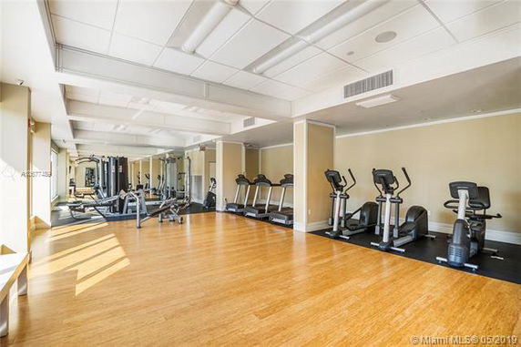 Indoor gym area with exercise machines and wooden flooring.