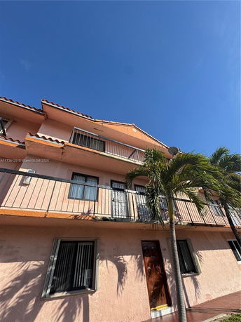 Front view of a multi-story building with balconies and a terracotta roof.