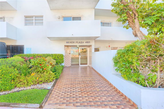 Front view of a building entrance labeled Beach Plaza 4101 with a tiled pathway and greenery.