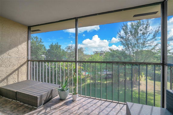Balcony view overlooking trees and grassy area.