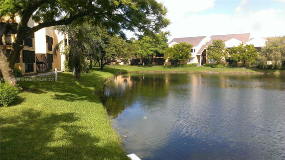 View of buildings near a pond with surrounding trees and greenery.