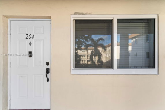 Front view of a section of a building with a white door labeled '204' and a window beside it.